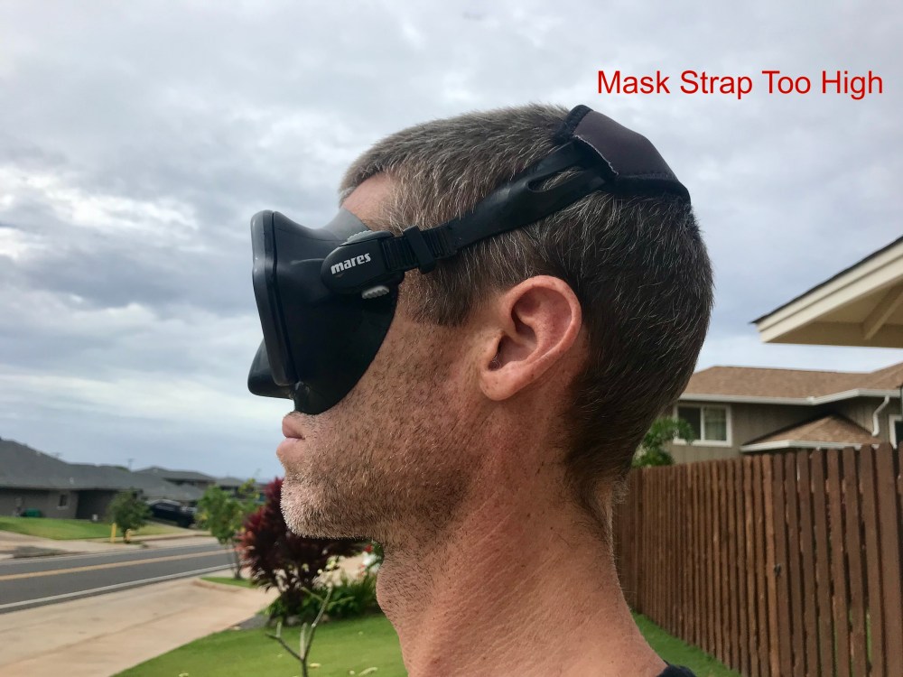 Side view of a person wearing a scuba mask with the strap angled toward the crown, labeled “Mask Strap Too High.”
