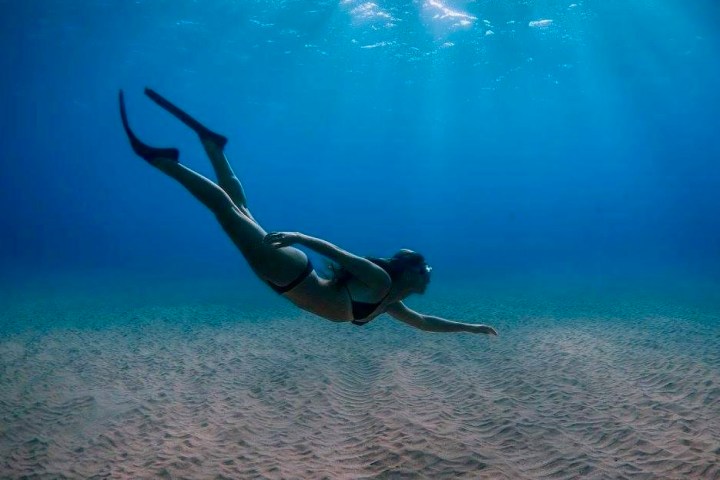 Snorkeler kicking over sand in Kaanapali, Hawaii.